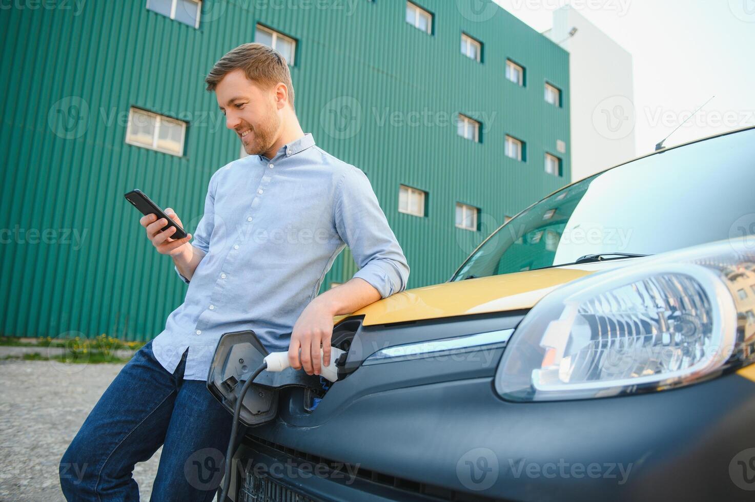 Smiling man unplugging the charger from the car photo