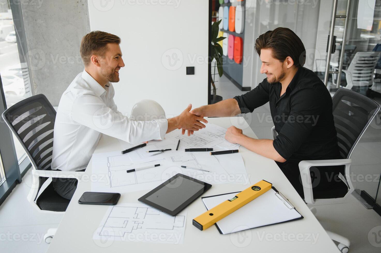 two people sit in front of construction plan and talk about the architecture photo
