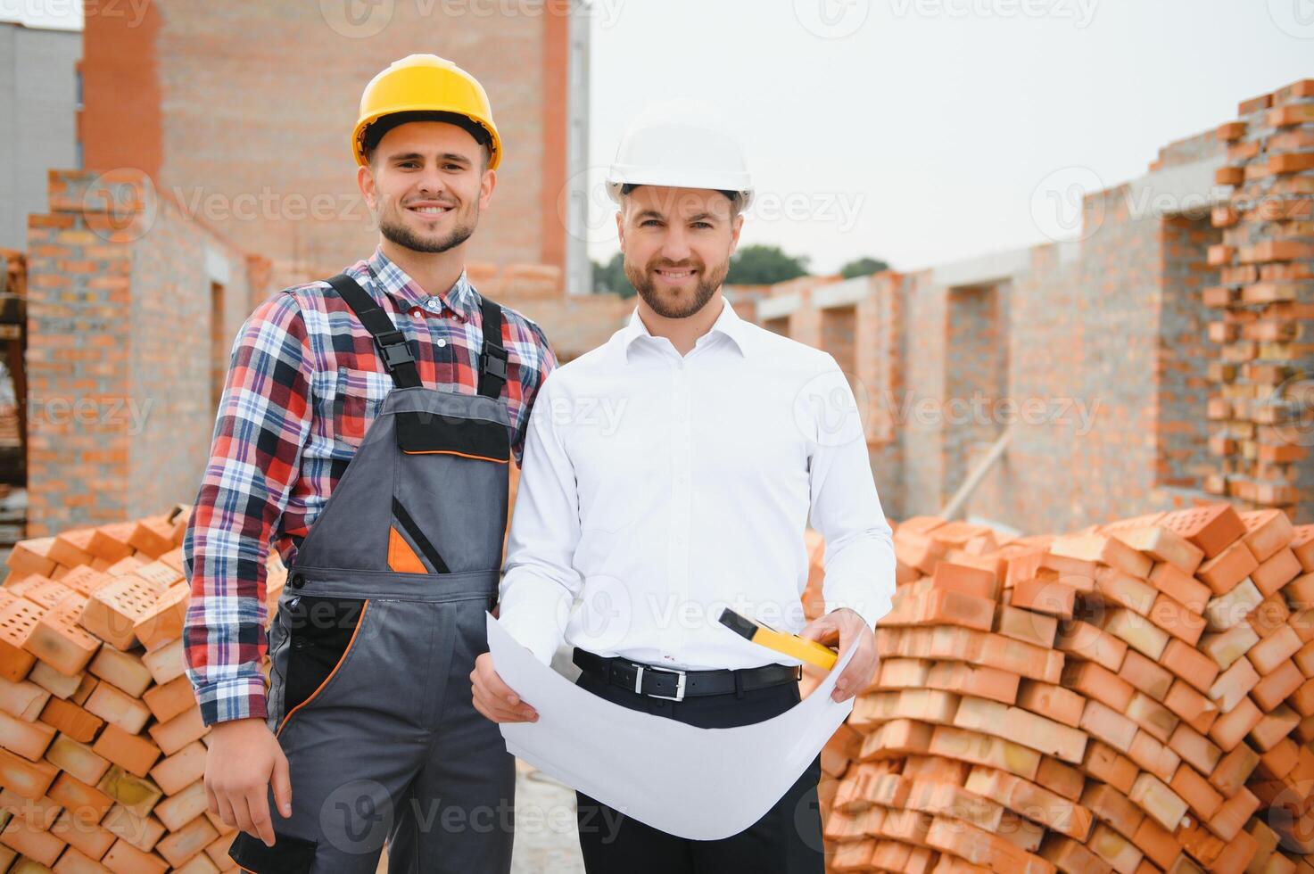 engineer architect with hard hat and safety vest working together in team on major construction site photo