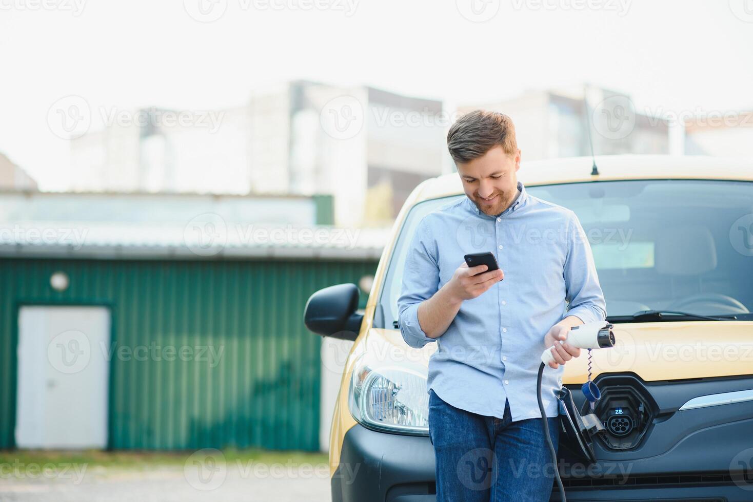 Smiling man unplugging the charger from the car photo