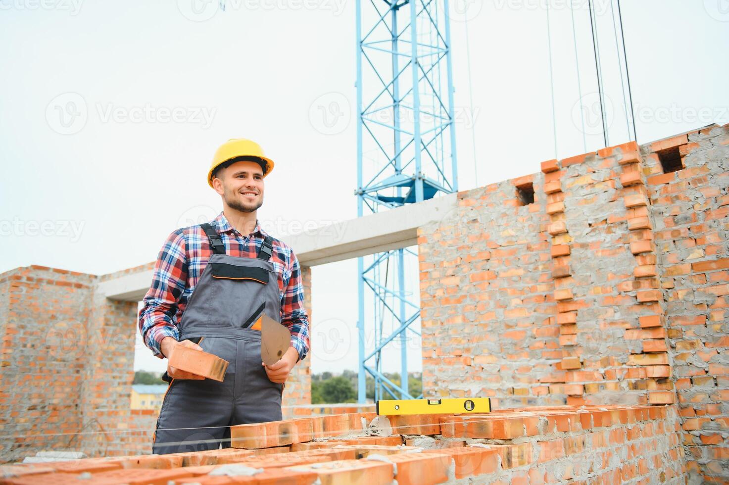 Construction worker man in work clothes and a construction helmet. Portrait of positive male builder in hardhat working at construction site. photo