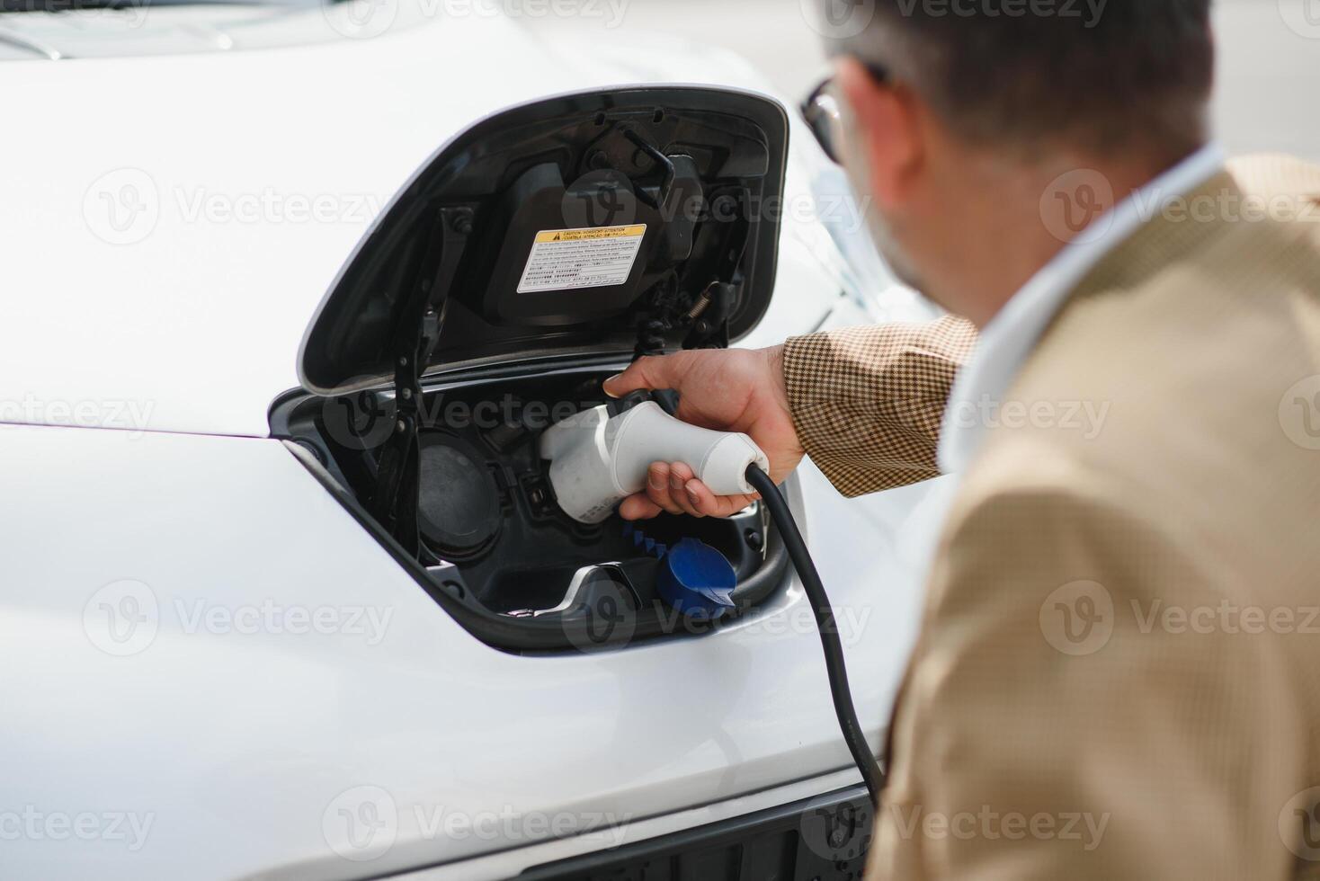 a businessman charges an electric car photo