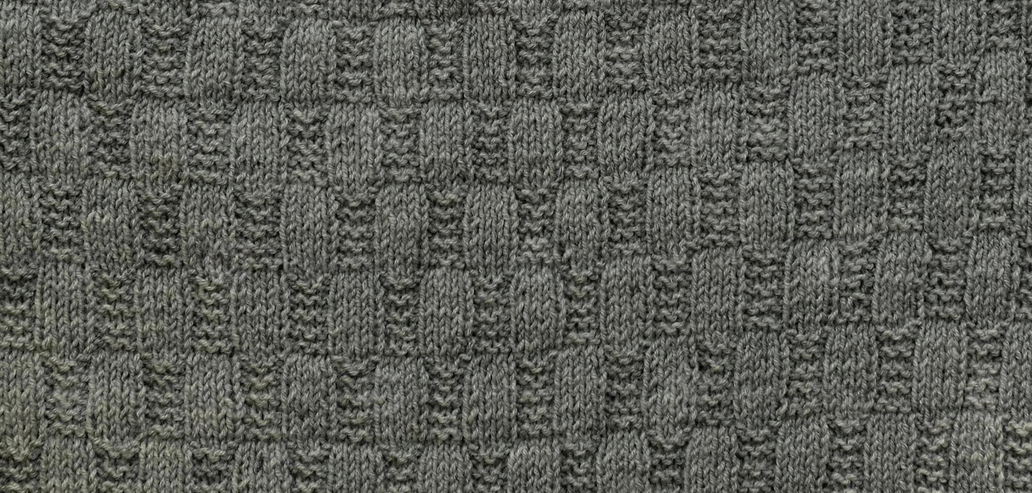 Background with gray knitted leaf shape, knitting pattern with cables. Top view, close-up. Handmade knitting wool photo