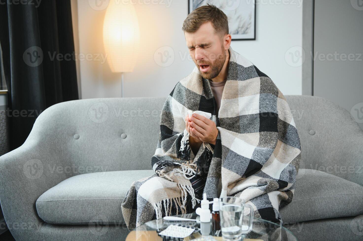 Sick man on sofa at home and blowing nose photo