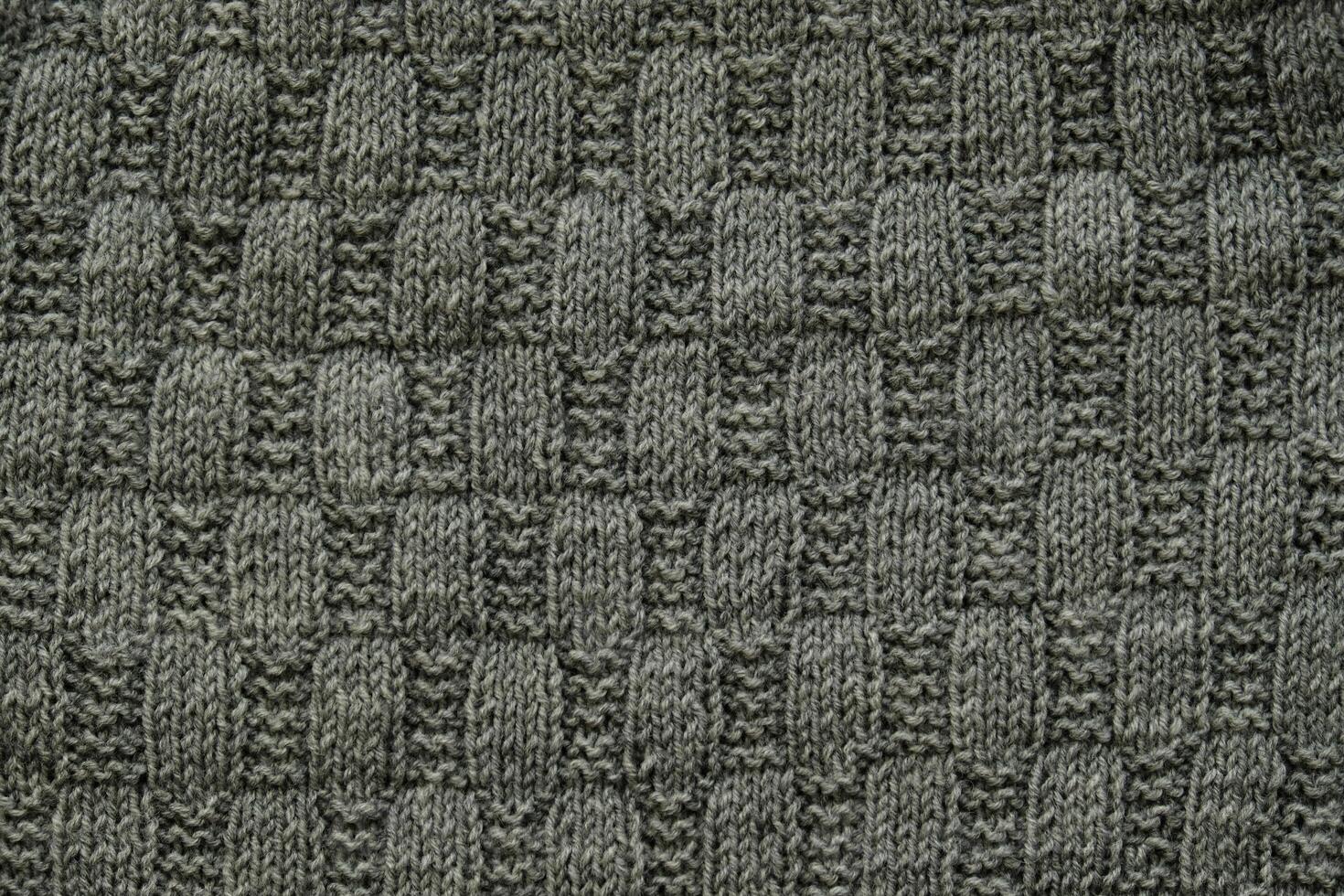 Background with gray knitted leaf shape, knitting pattern with cables. Top view, close-up. Handmade knitting wool photo