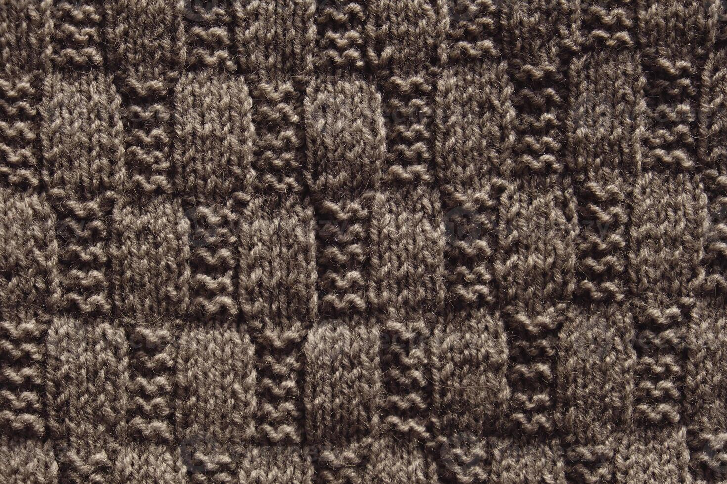 Background with gray knitted leaf shape, knitting pattern with cables. Top view, close-up. Handmade knitting wool photo