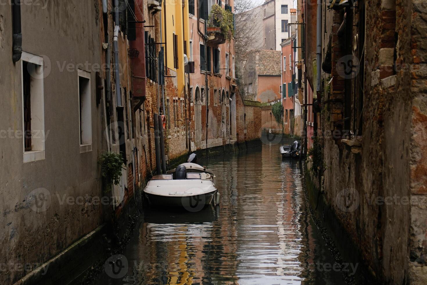 Typical narrow streets and canals between colorful and shabby houses in Venice, Italy. Historical architecture in Venice, parked boats on the canals. photo
