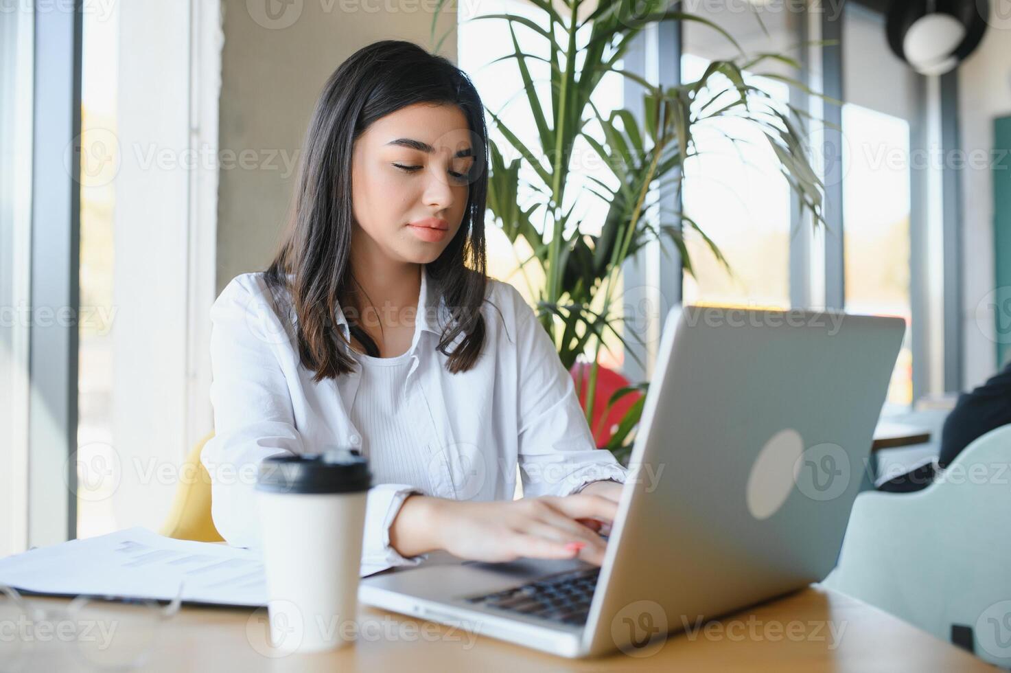 Joyful girl student studying online at cafe, using laptop and earphones, empty space photo
