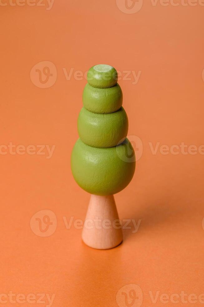 Wooden model of a tree with a green crown and trunk on a orange background photo
