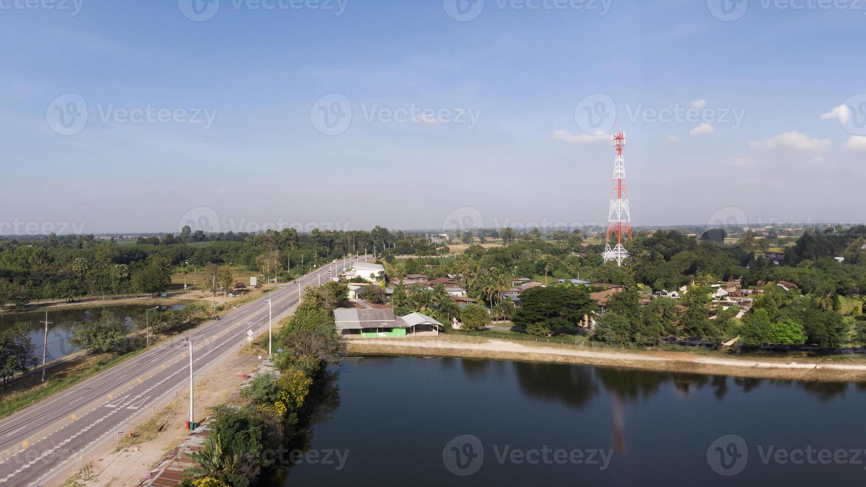 zumbido Disparo escénico paisajes escenario, rural pueblos allí estaba un ligeramente nublado cielo, un estanque, y un autopista corriendo mediante eso foto