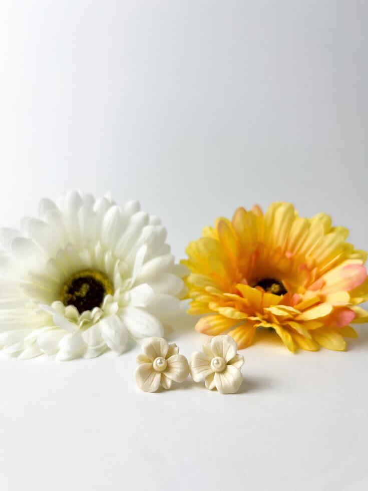 White small earrings pair fashion accesories. Earwear object photography isolated on white studio background with flower decorations. photo