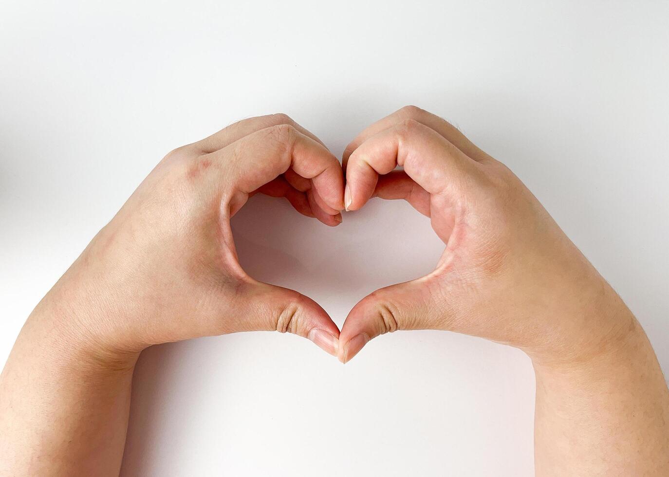 Light skin toned human hand with love and heart pose gesture isolated on horizontal white studio background. Healthcare, valentine or romance, and charity care themed photography. photo