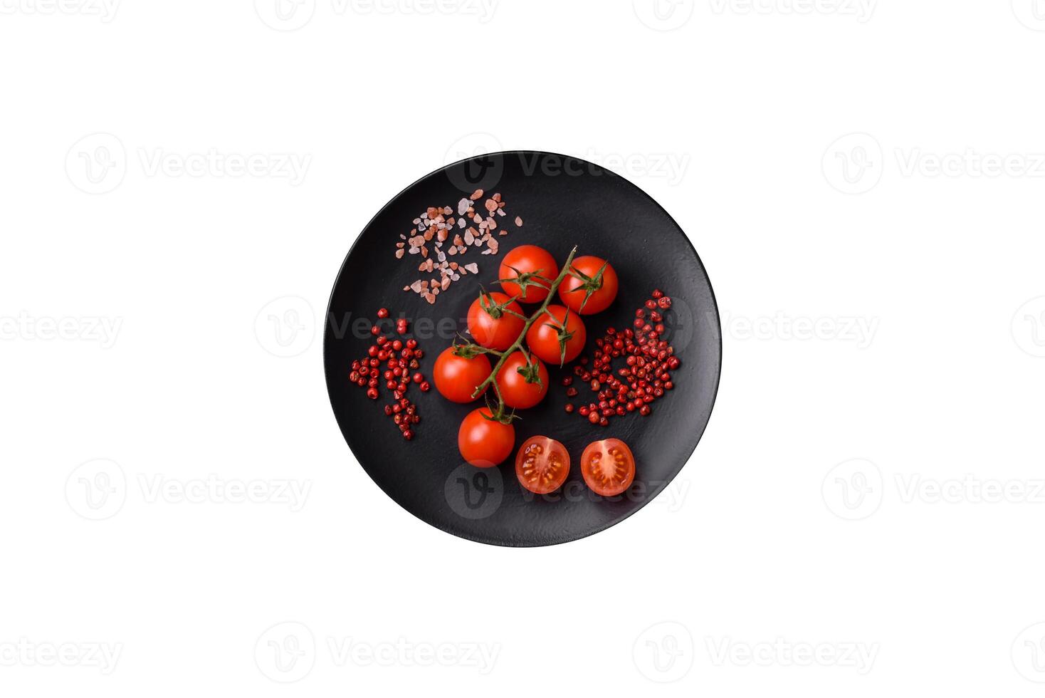 A branch of raw cherry tomatoes with salt and spices on a dark background photo