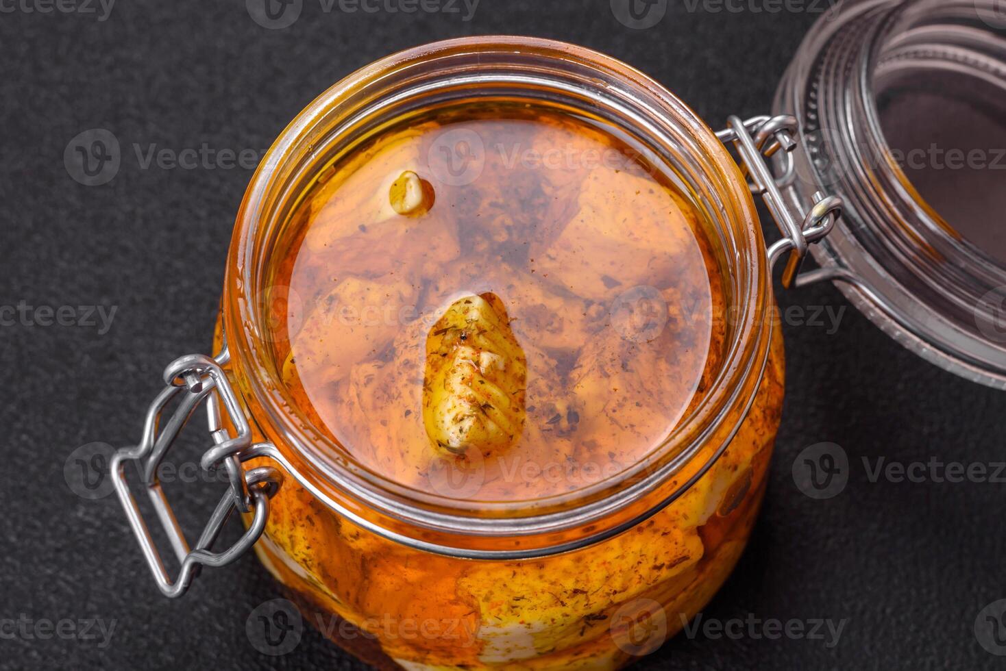 Delicious soft white feta cheese with salt, spices and herbs on a dark concrete background photo