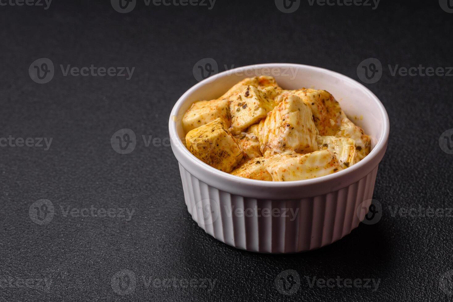 Delicious soft white feta cheese with salt, spices and herbs on a dark concrete background photo