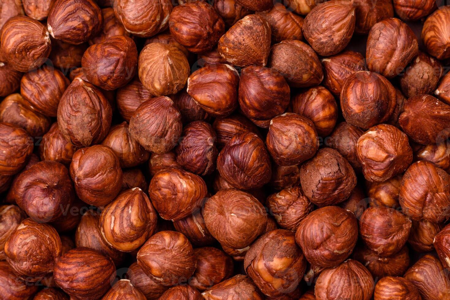 Delicious hazelnut whole, raw, without shell, on a dark concrete background photo