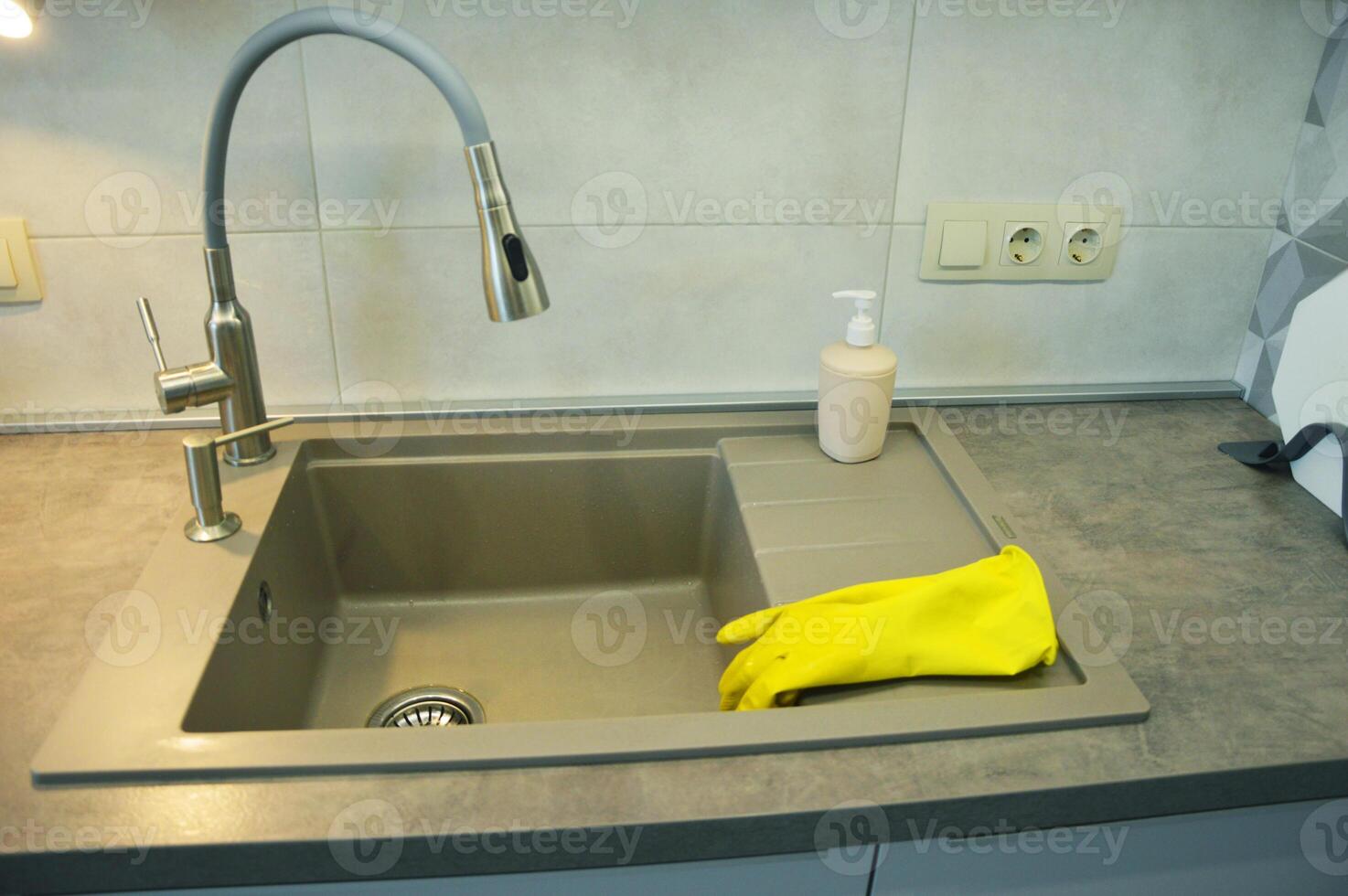 Yellow household cleaning gloves lie on the kitchen sink. photo