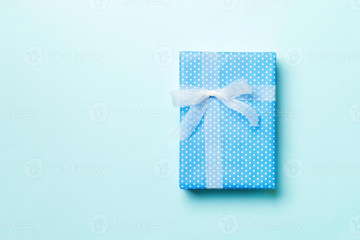 Top view Christmas present box with white bow on blue background with copy space photo