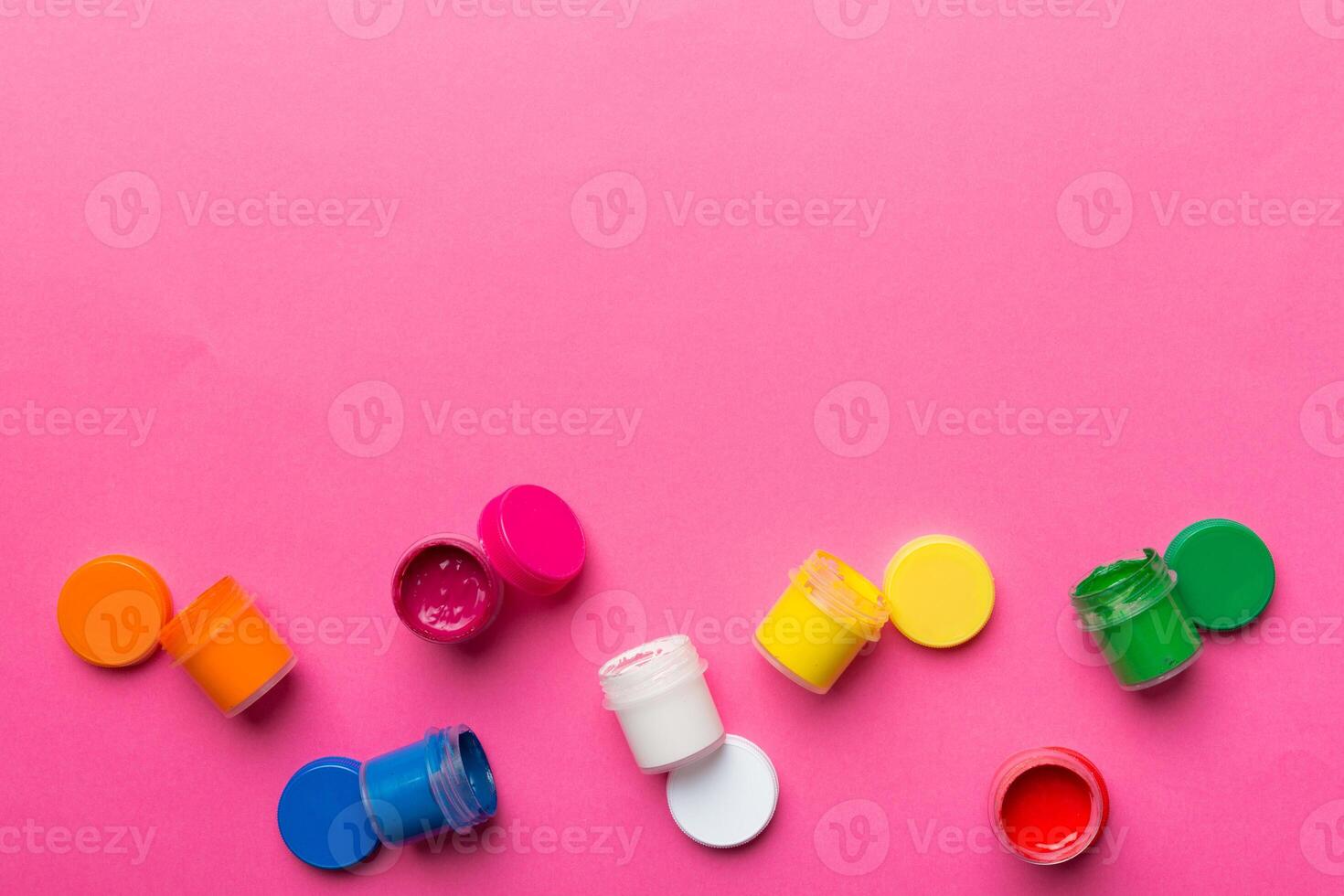 jars with gouache of different colors on Colored background. hobby painting. Top view with empty space. workplace for creativity. home teaching concept drawing photo