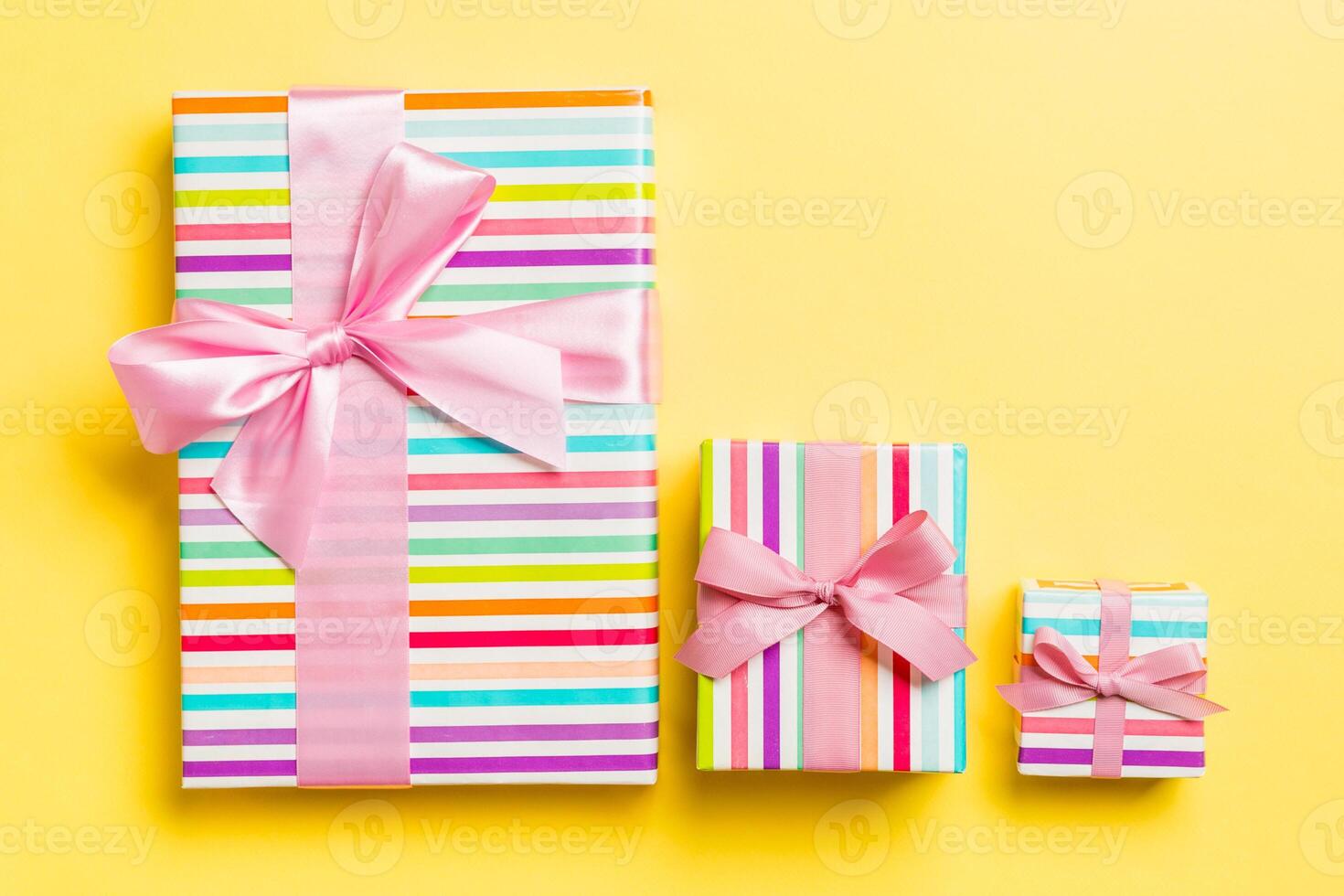 Gift box with pink bow for Christmas or New Year day on yellow background, top view photo