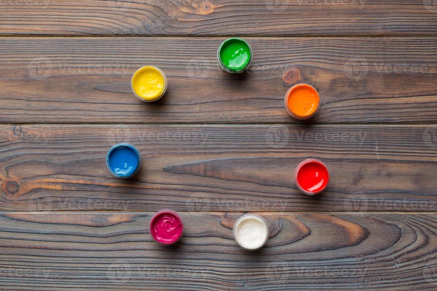 jars with gouache of different colors on Colored background. hobby painting. Top view with empty space. workplace for creativity. home teaching concept drawing photo