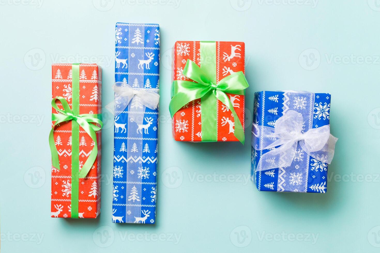 wrapped Christmas or other holiday handmade present in paper with white and green ribbon on blue background. Present box, decoration of gift on colored table, top view photo