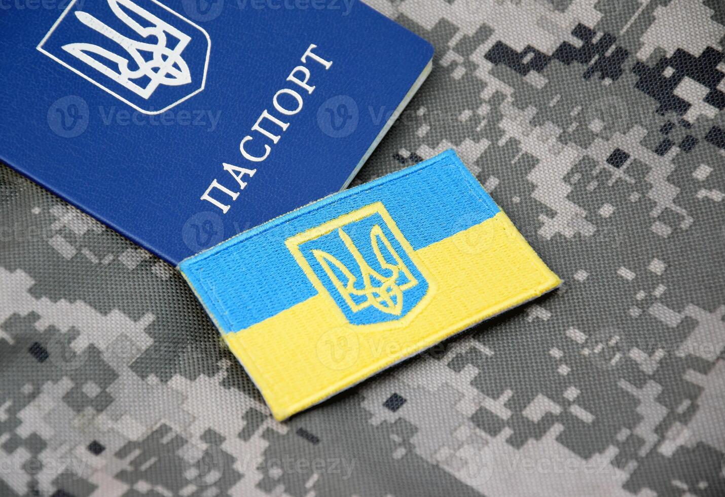 Ukrainian passport and flag with the coat of arms of Ukraine on the background of military camouflage. photo