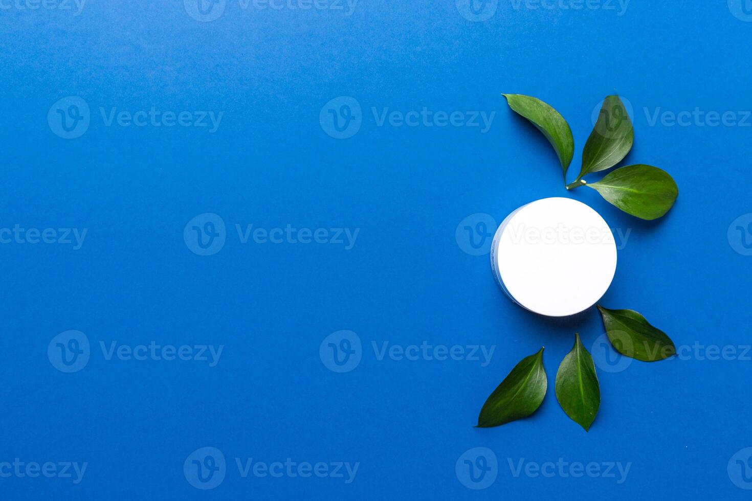Organic cosmetic product with green leaves on color background. Copy space, flat lay photo