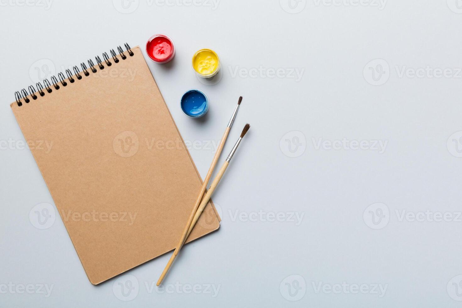 Album pages and paints, pencils, brush on a colored background. Top view with empty space. workplace for creativity. home teaching concept drawing photo