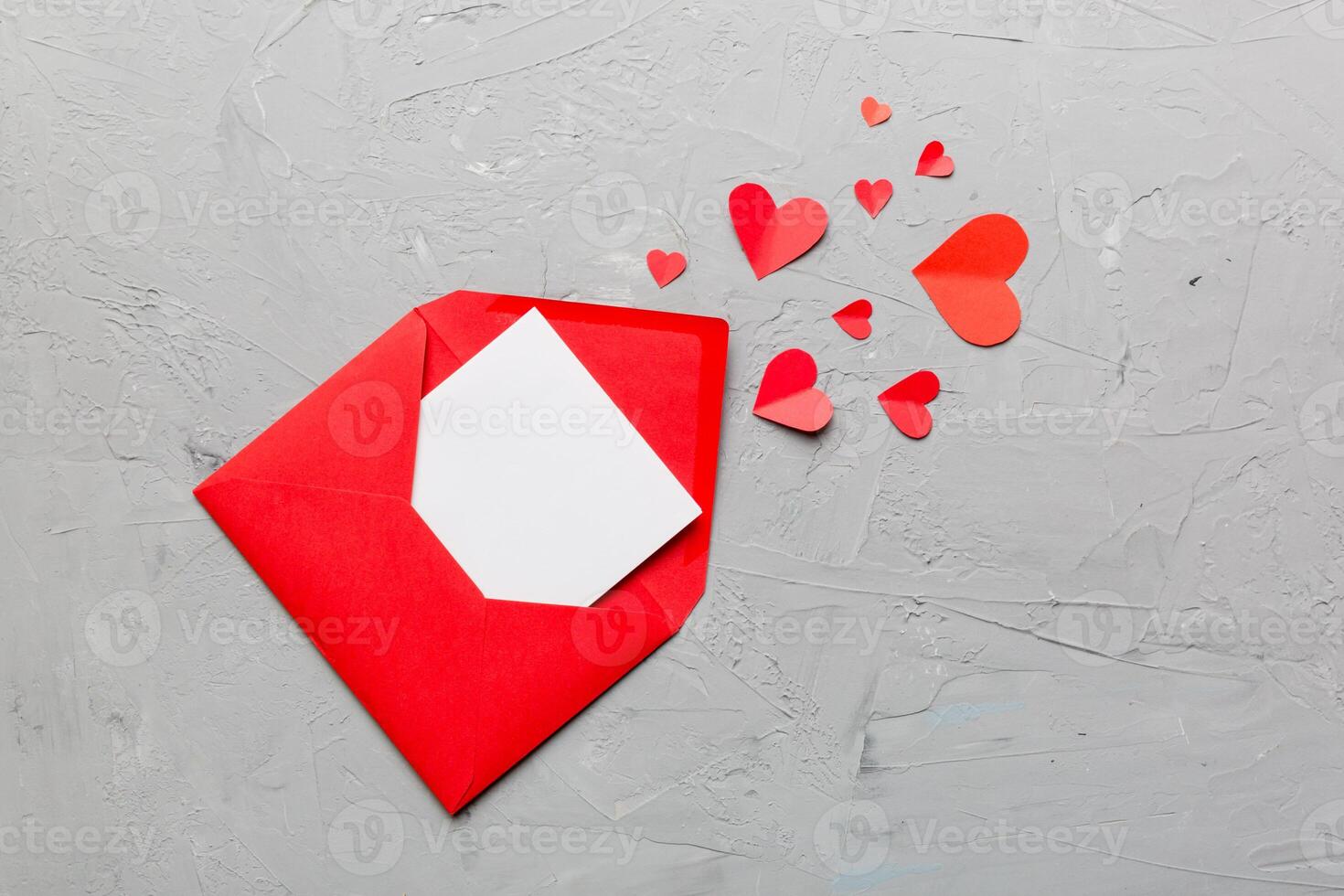 Red paper envelope with empty white card and heart on colored background. top view valentines day concept photo