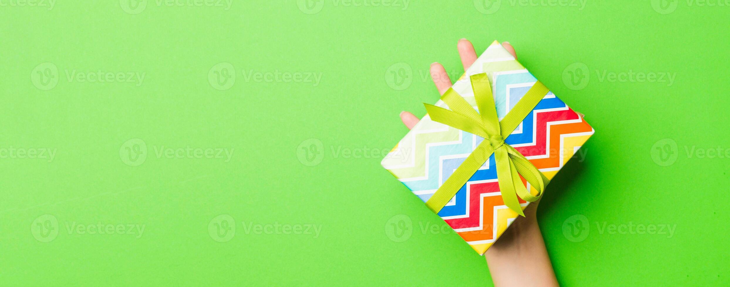 Top view of female hands holding christmas or other holiday handmade present box package in the palms, flat lay table background with copy space photo