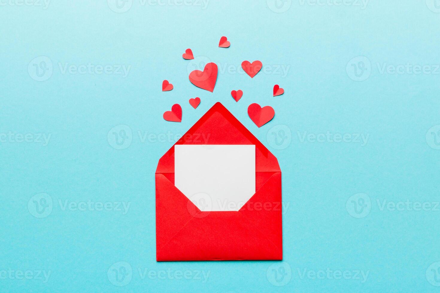 Red paper envelope with empty white card and heart on colored background. top view valentines day concept photo