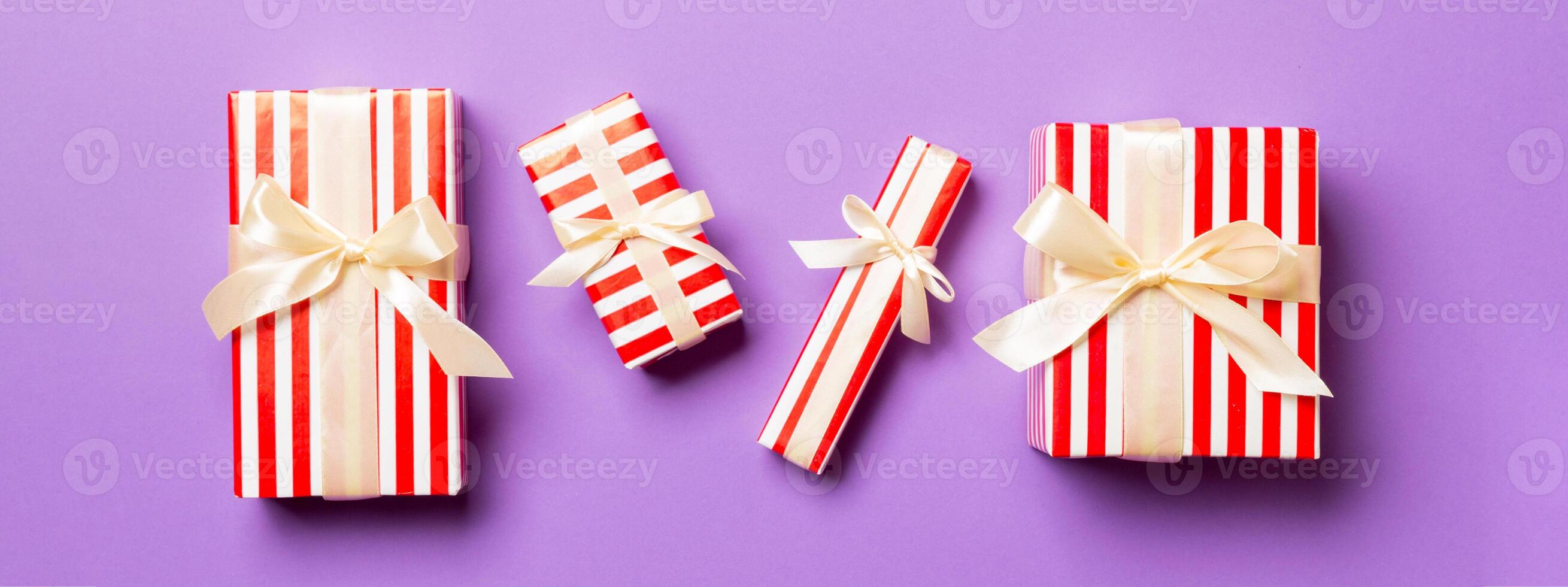 wrapped Christmas or other holiday handmade present in paper with yellow ribbon on purple background. Present box, decoration of gift on colored table, top view photo