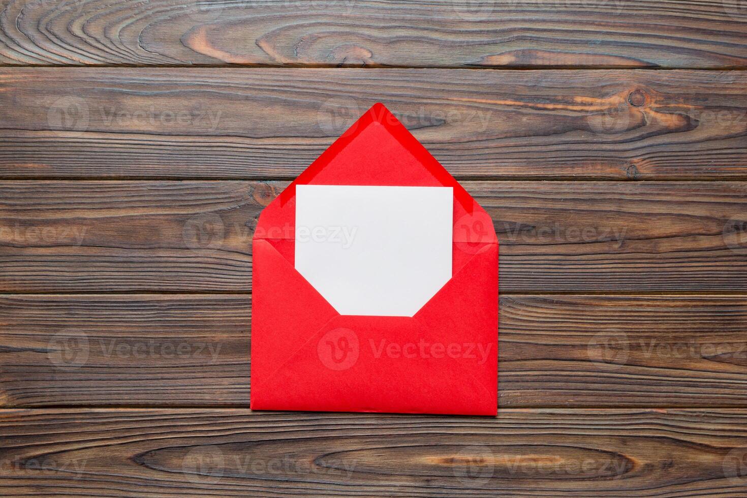 Red paper envelope with empty white card and heart on colored background. top view valentines day concept photo