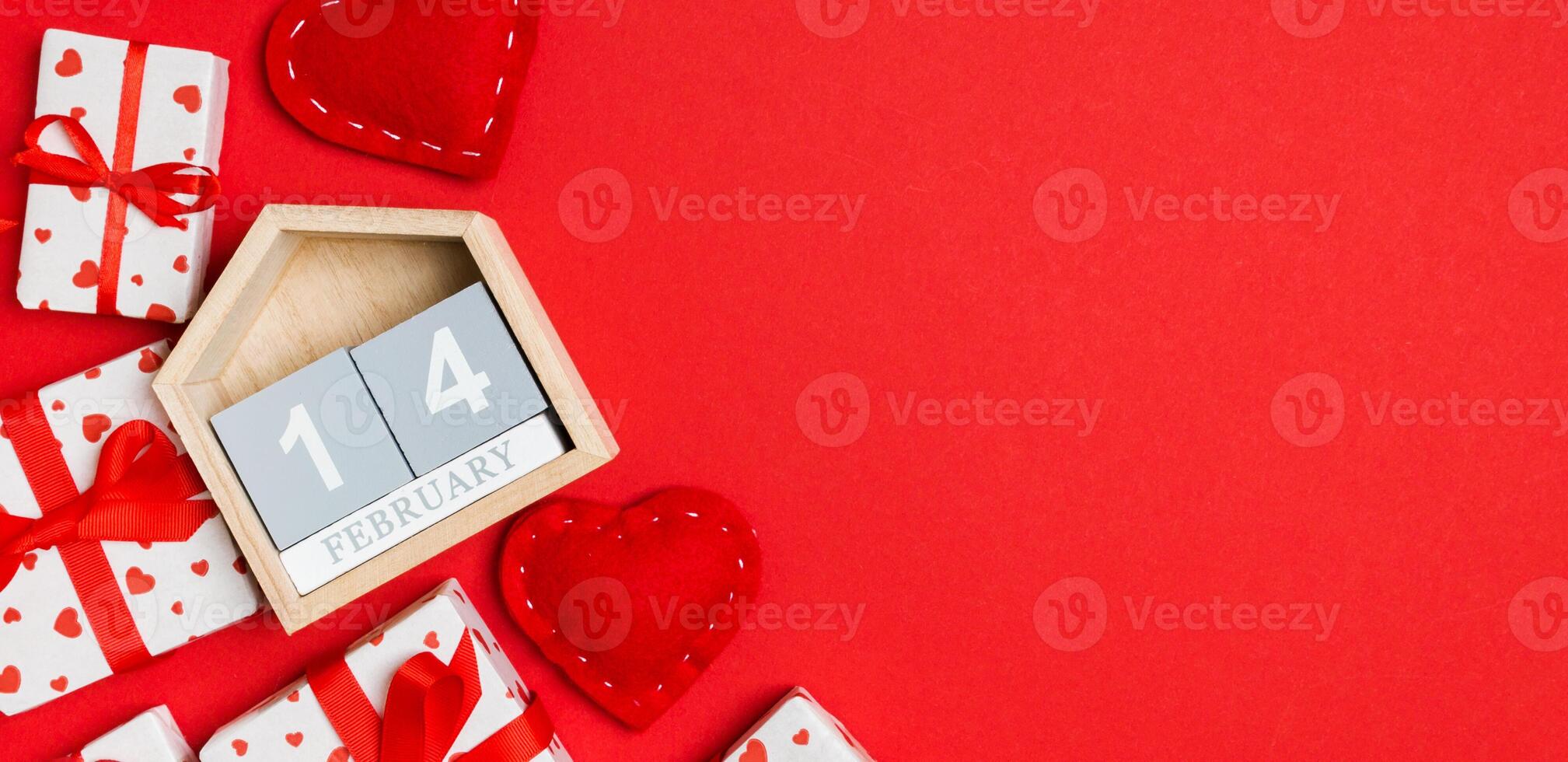 vista superior de cajas de regalo, calendario de madera y corazones textiles rojos sobre fondo colorido. catorce de febrero. concepto del día de san valentín con espacio de copia foto