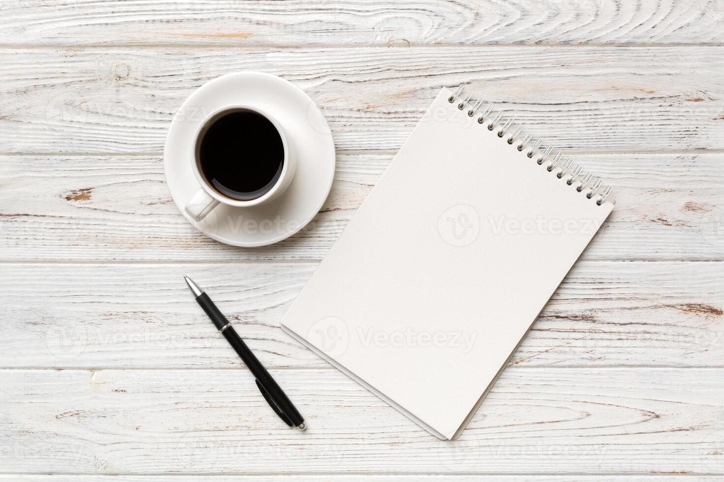 Modern office desk table with notebook and other supplies with cup of coffee. Blank notebook page for you design. Top view, flat lay photo