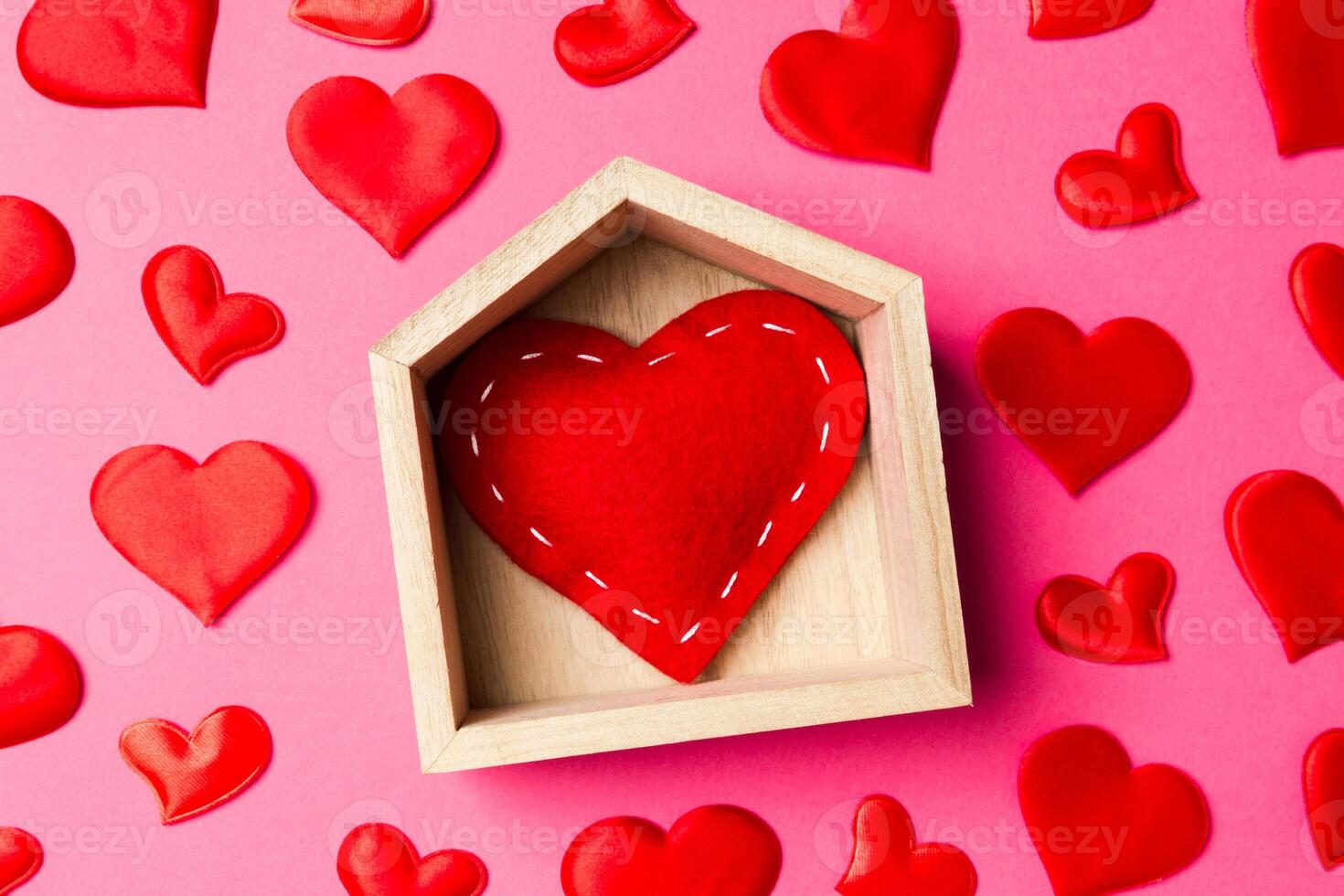 Close up of red heart in a wooden house decorated with small hearts on colorful background. Valentine's day. Home sweet home concept photo