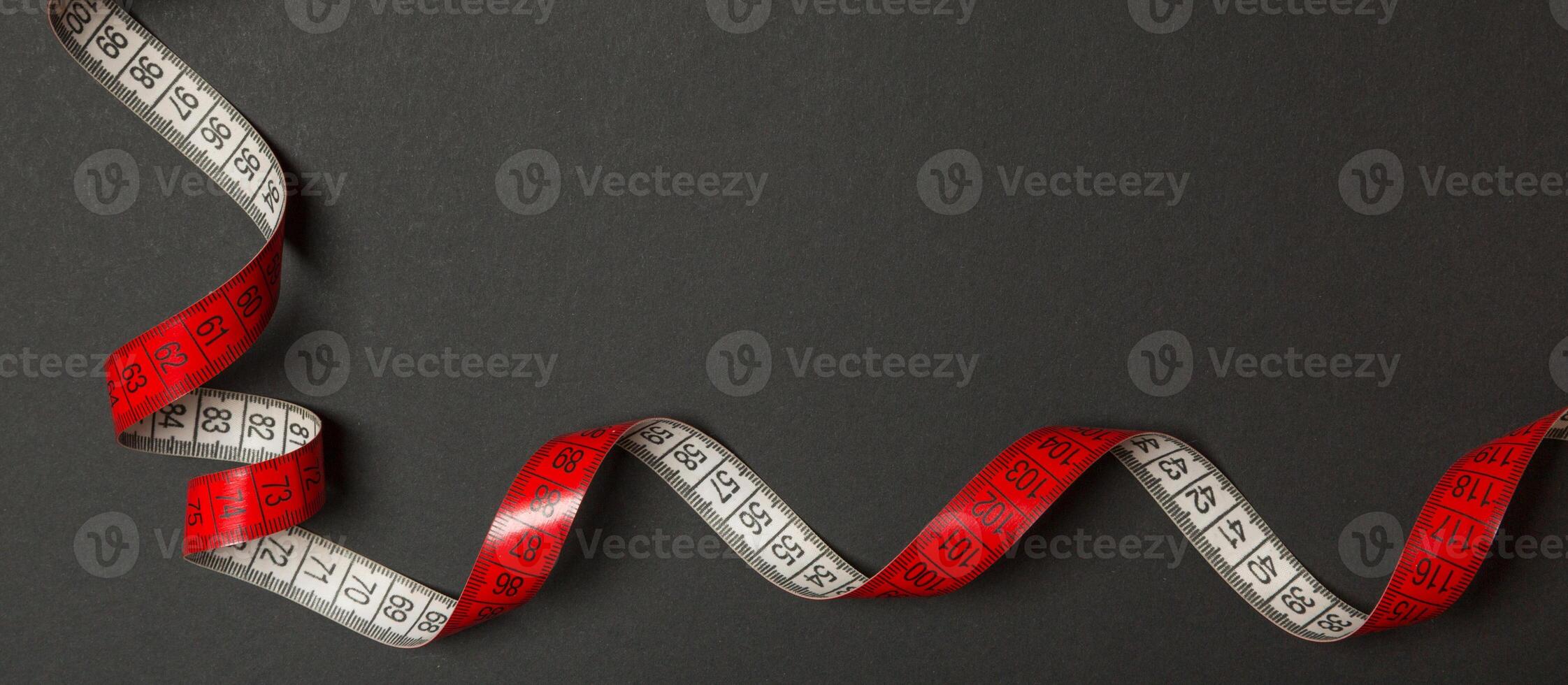 Frame made of measuring tape on black background. Top view of sewing concept. Slim waist concept with empty space for your design photo