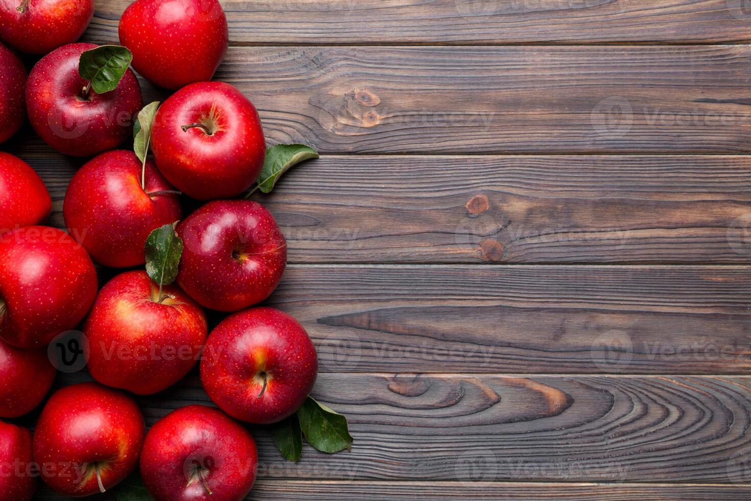 Fresh red apples with green leaves on wooden table. On wooden background. Top view free space for text photo