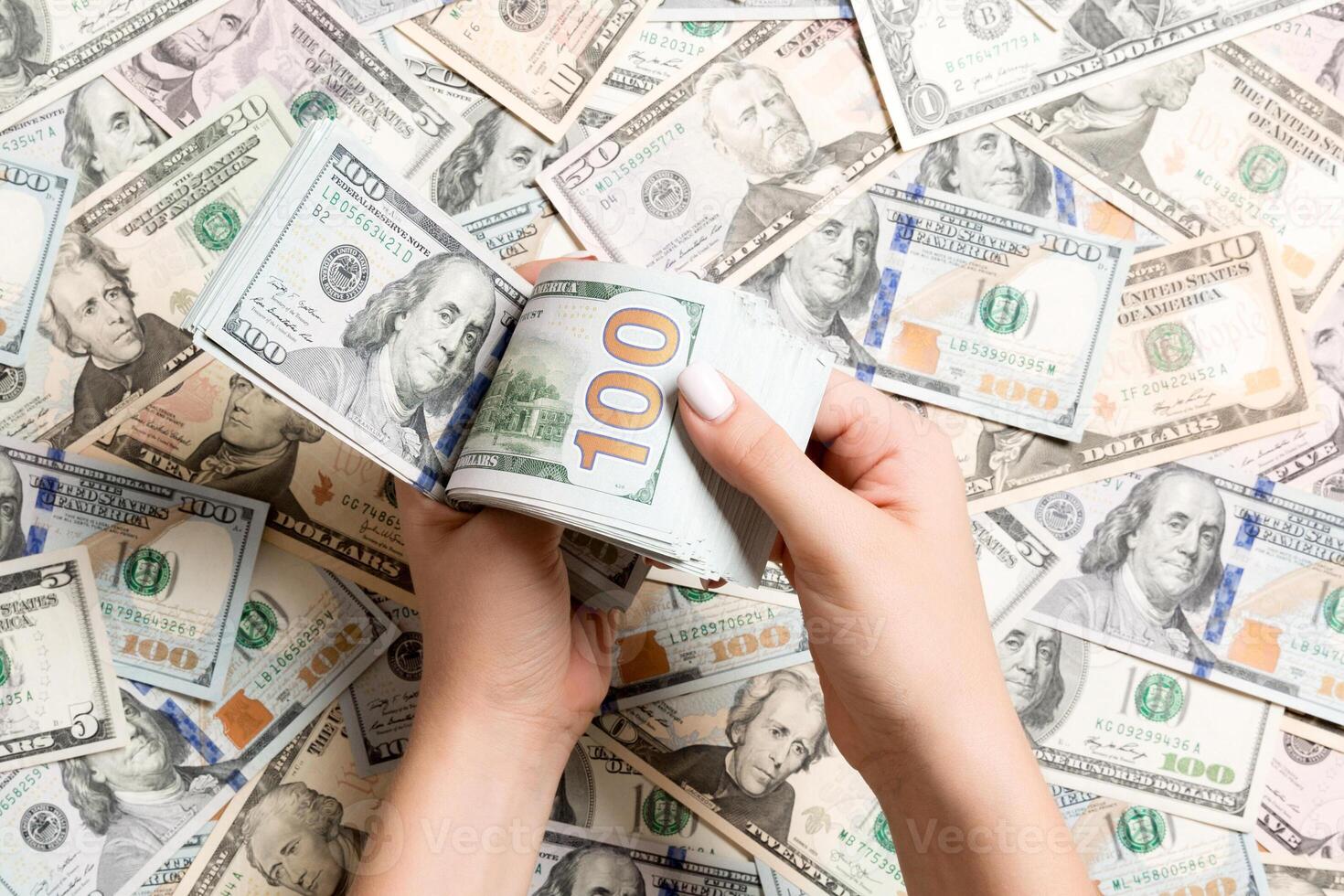 Top view of female hands counting money on different dollar background. Debt concept. Investment concept photo