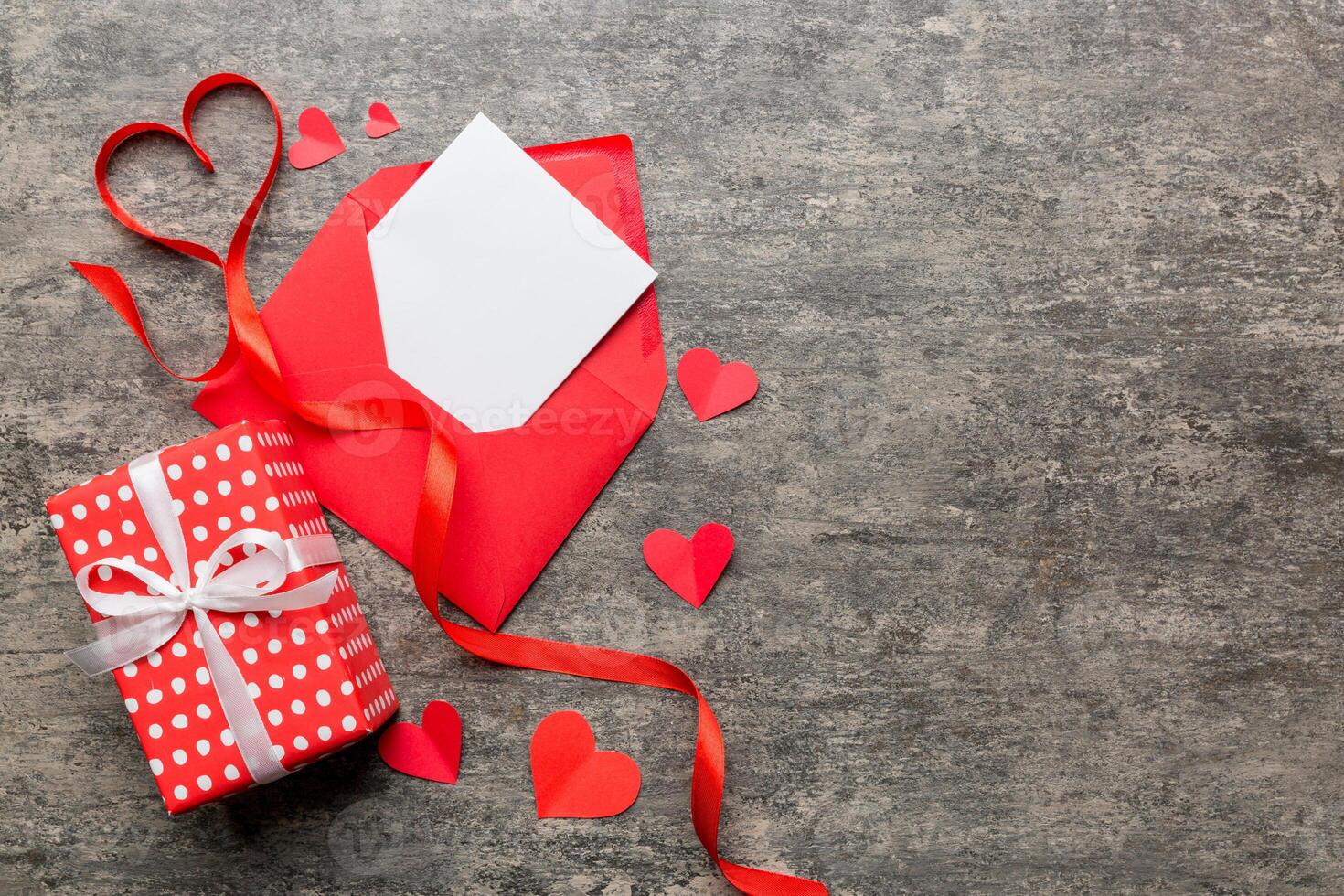 Red paper envelope with empty white card and heart on colored background. top view valentines day concept photo