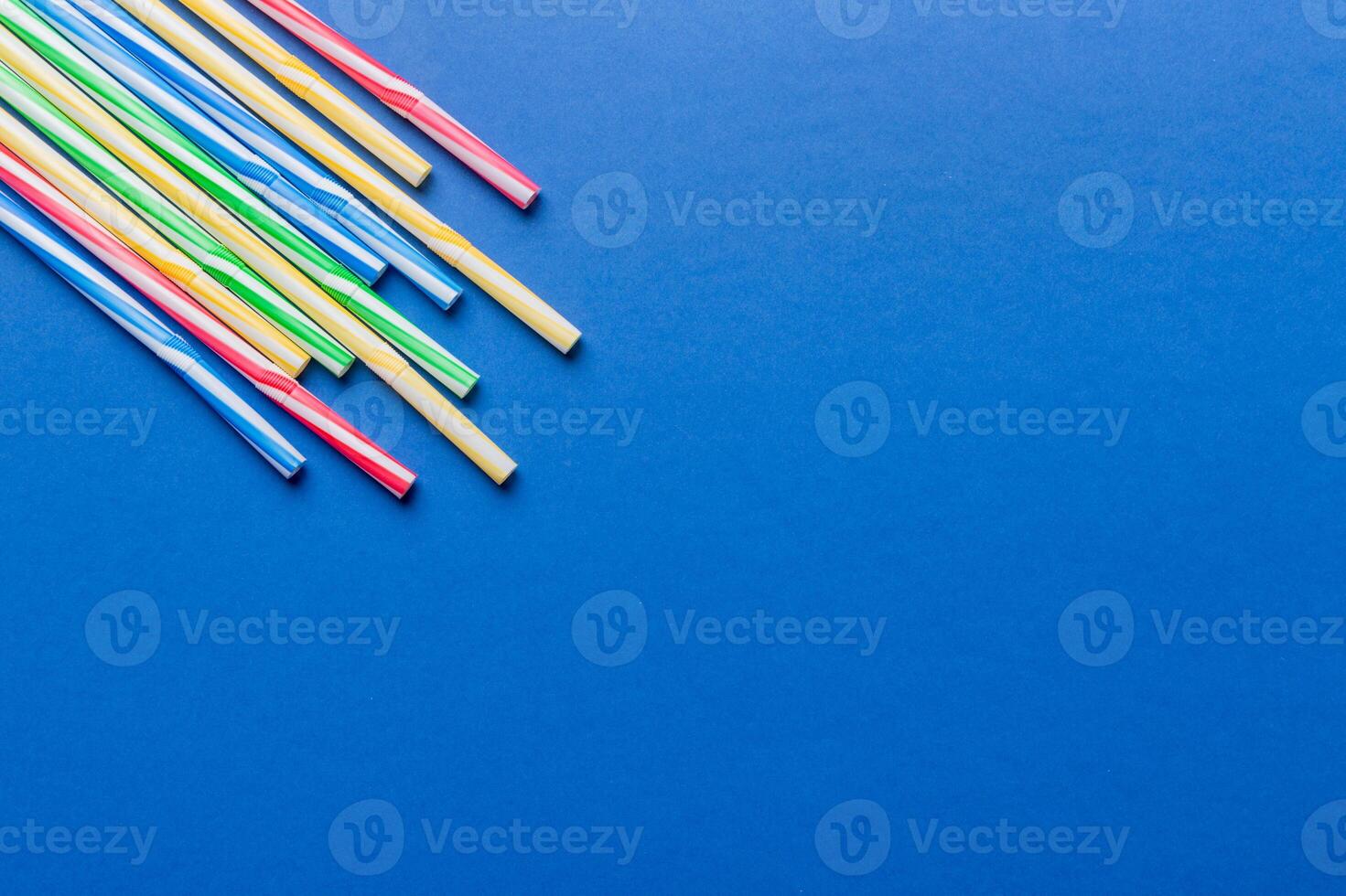 Heap of colorful plastic drinking straws on Colored background, flat lay. Copy Space for text photo