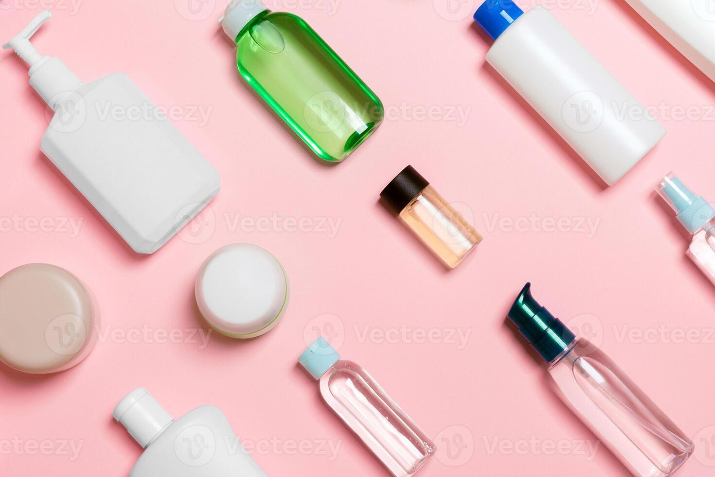 Top view of different cosmetic bottles and container for cosmetics on pink background. Flat lay composition with copy space photo