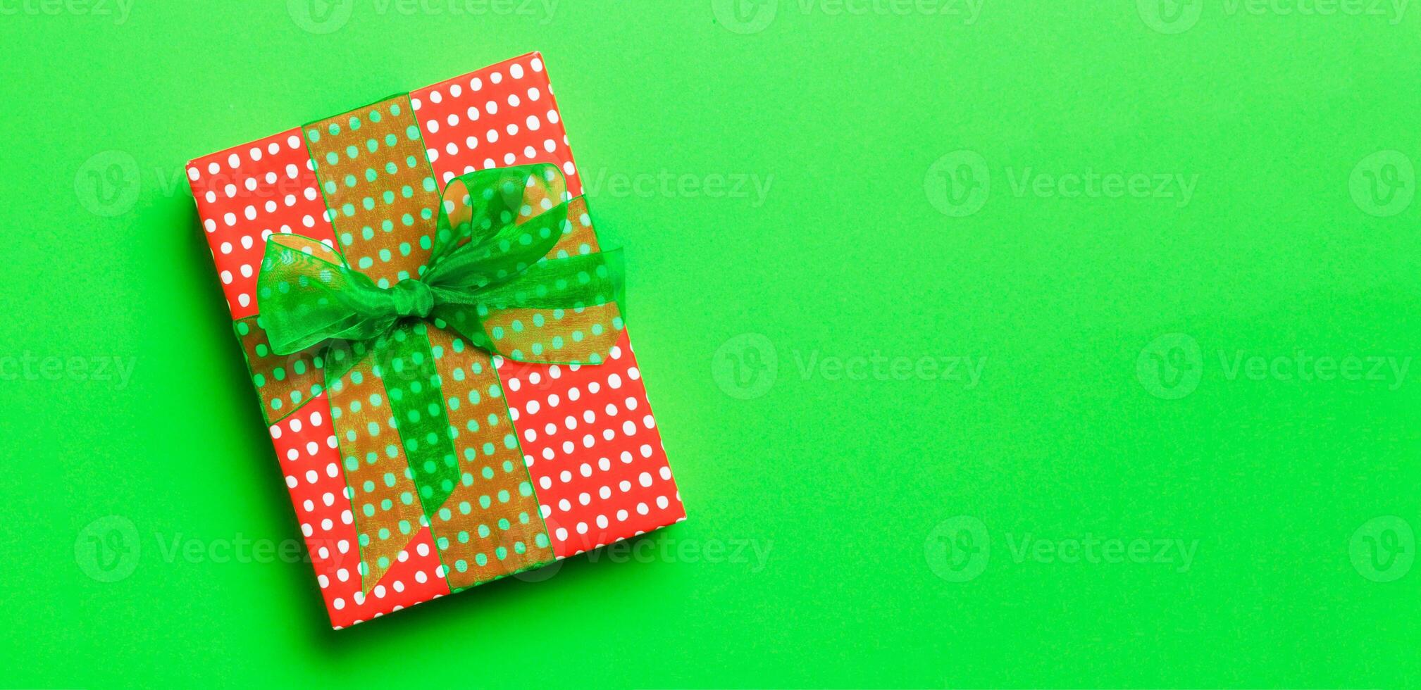 Top view Christmas present box with green bow on green background with copy space photo