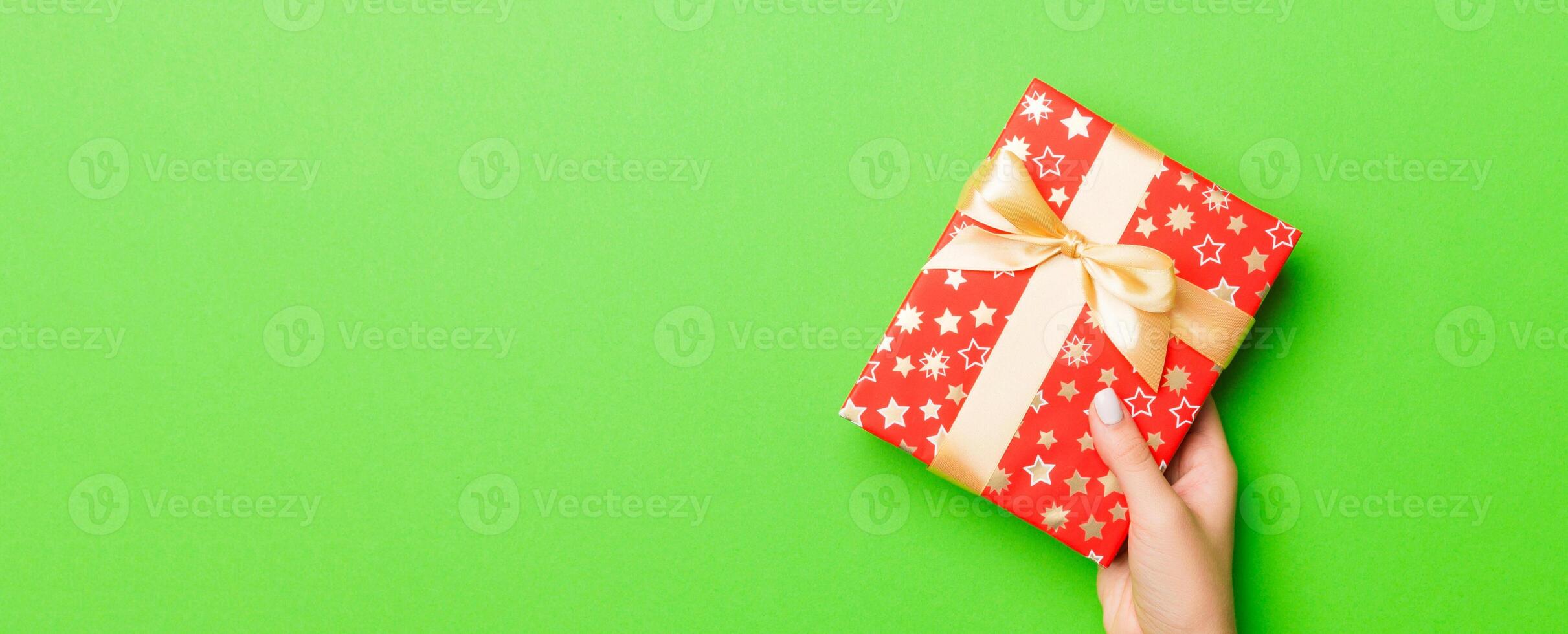 Top view of female hands holding christmas or other holiday handmade present box package in the palms, flat lay table background with copy space photo