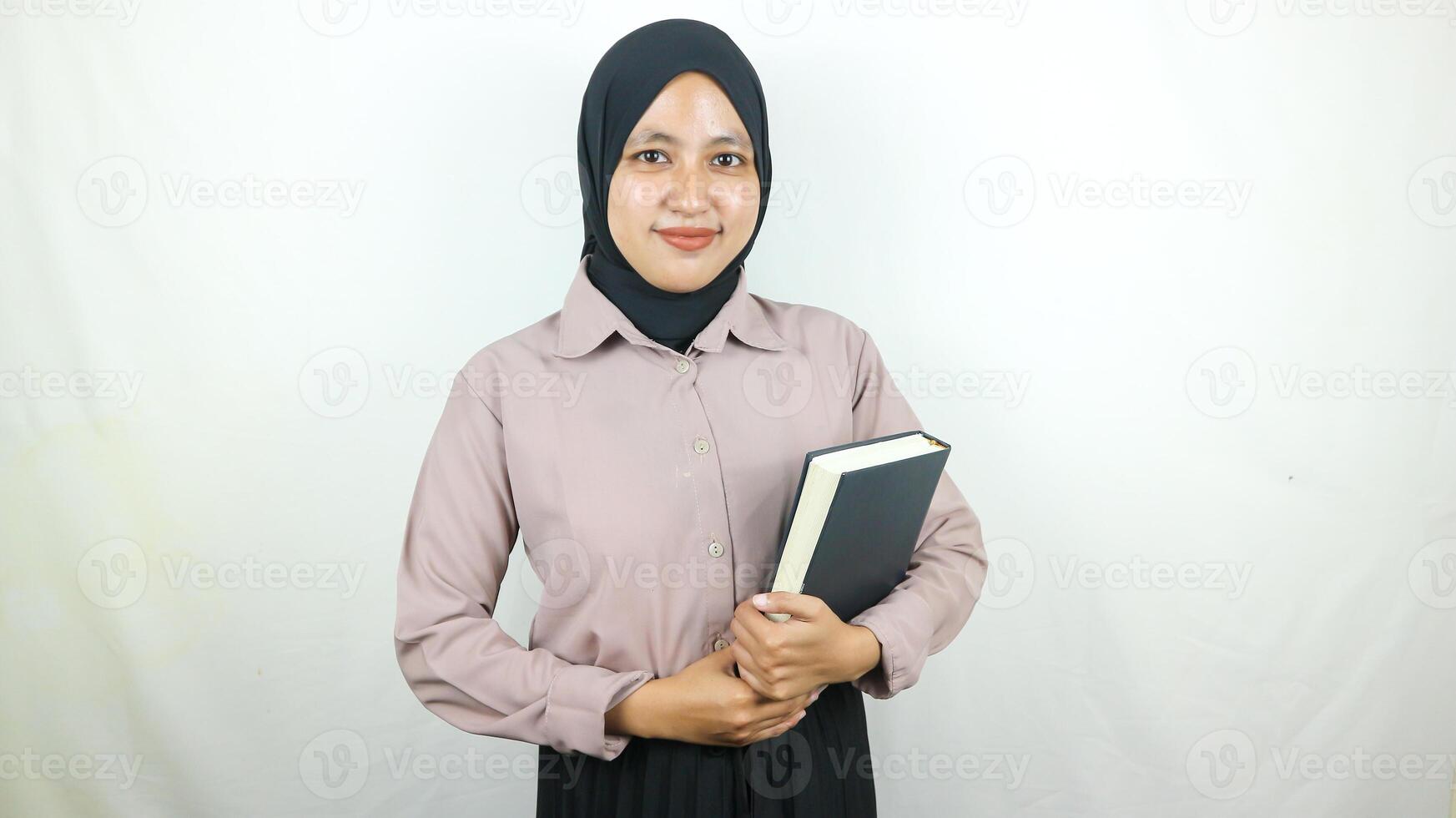 sonriente joven asiático musulmán estudiante participación libro, mirando a cámara aislado en blanco antecedentes. foto