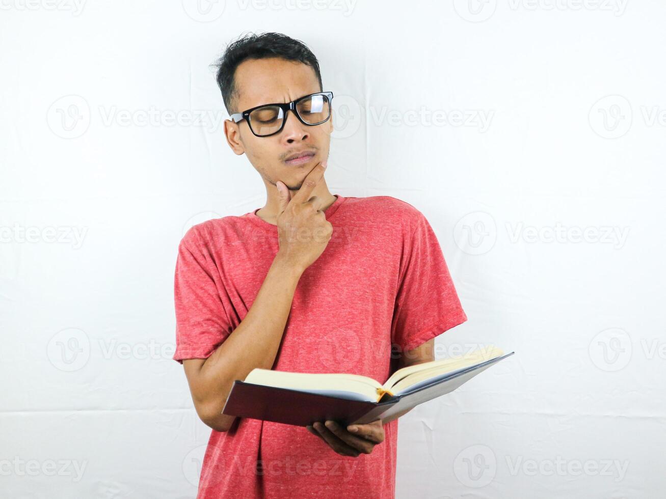 Portrait of Asian man holding book with thinking face expression photo