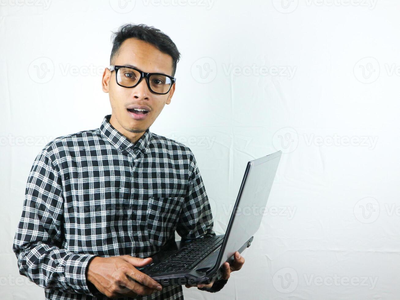 retrato de asiático hombre participación ordenador portátil con sorprendido expresión. publicidad concepto. foto