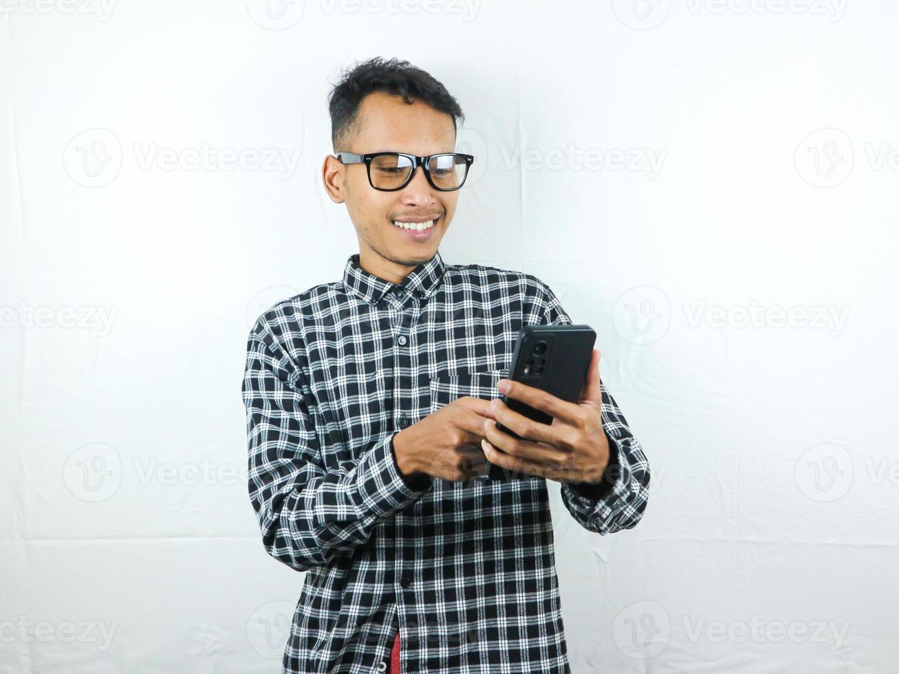 Portrait of asian man using hand phone and scrolling screen with smiling expression reading message. photo
