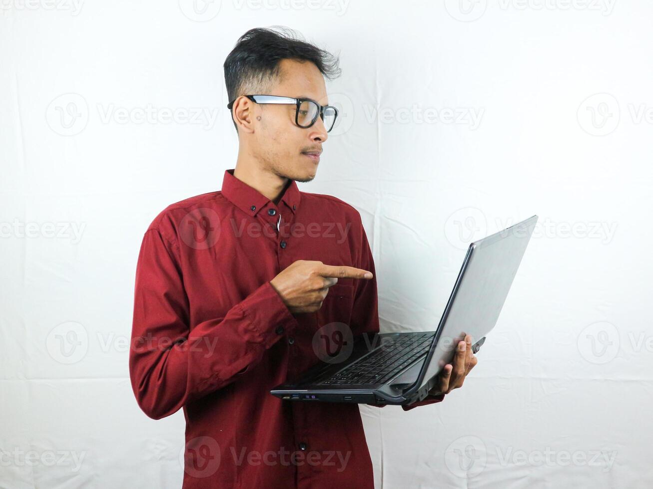 retrato de asiático hombre participación ordenador portátil y señalando a pantalla con enfocado expresión. foto